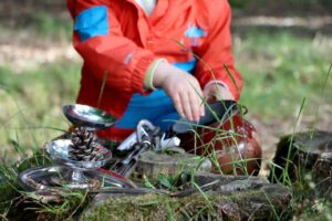 On voit les mains d'un enfant, dehors, qui joue avec des éléments du quotidien, dans le cadre de la dynamique portée par le GRAINE Pays de la Loire, Petite enfance en nature